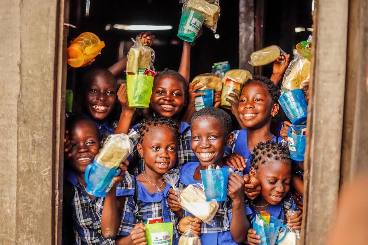 services-02 Group of happy children holding food packages and smiling outdoors.