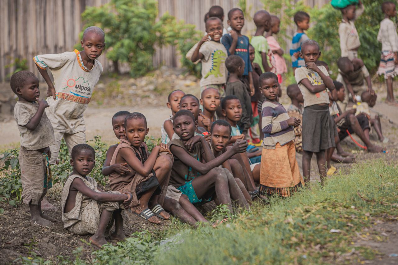 portfolio-01 A group of children sitting and standing together outdoors, showcasing community and togetherness.