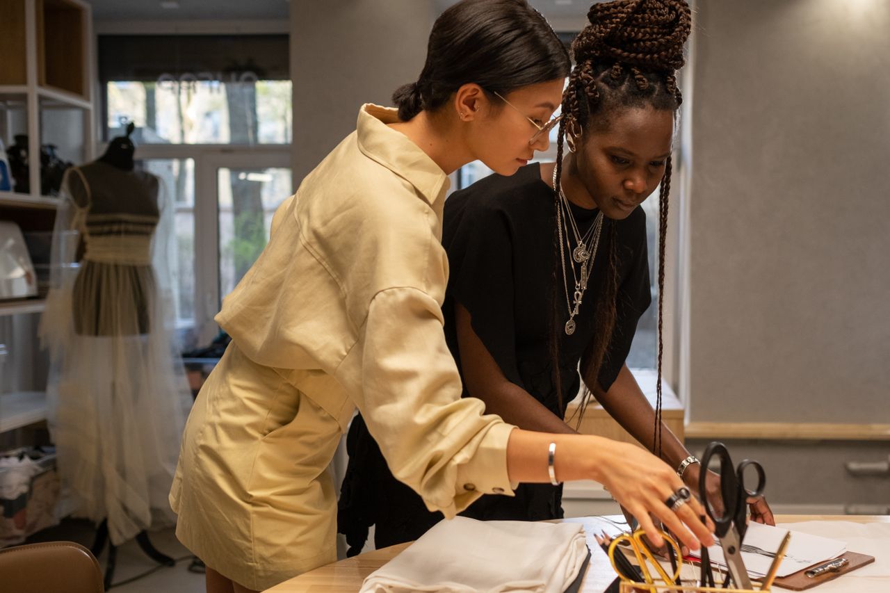 gallery-02 Two female fashion designers working together in an atelier environment, discussing and creating designs.